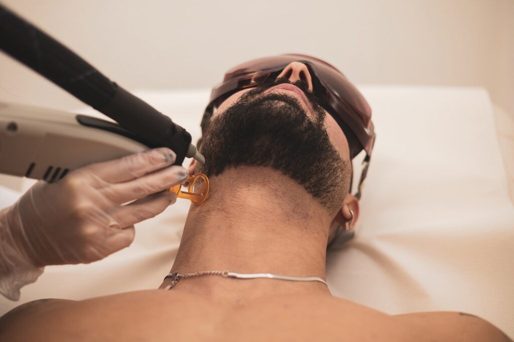handsome young man receiving laser skin treatment on his face. healthy lifestyle man concept